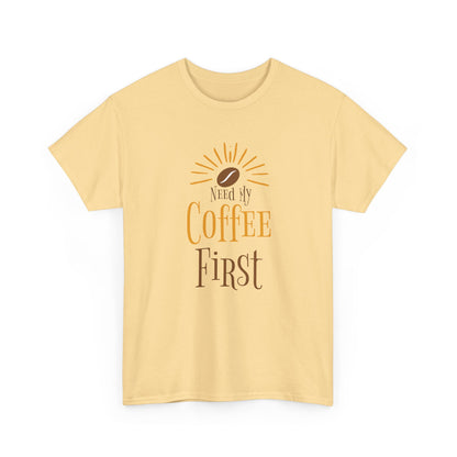 Yellow t-shirt with 'Need My Coffee First' text and coffee bean graphic on a white background