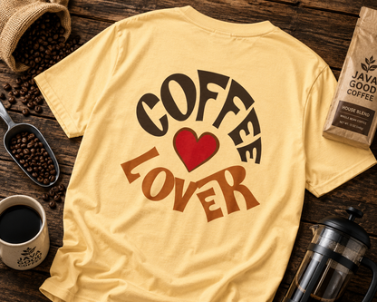 Yellow t-shirt with 'Coffee Lover' text on a wooden surface with coffee beans and a coffee bag.